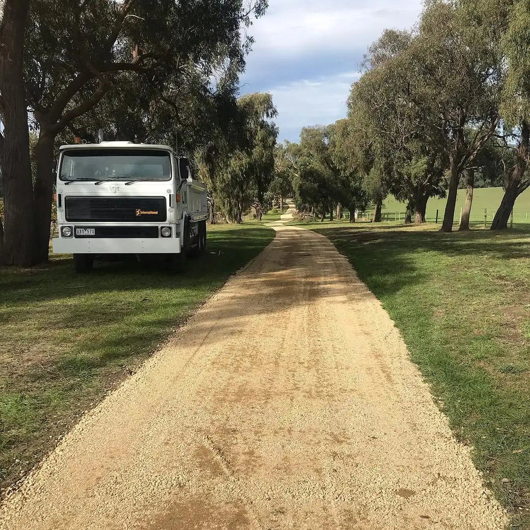 Long straight gravel driveway at Coldstream running between gum trees and paddock, with a truck parked on the grass