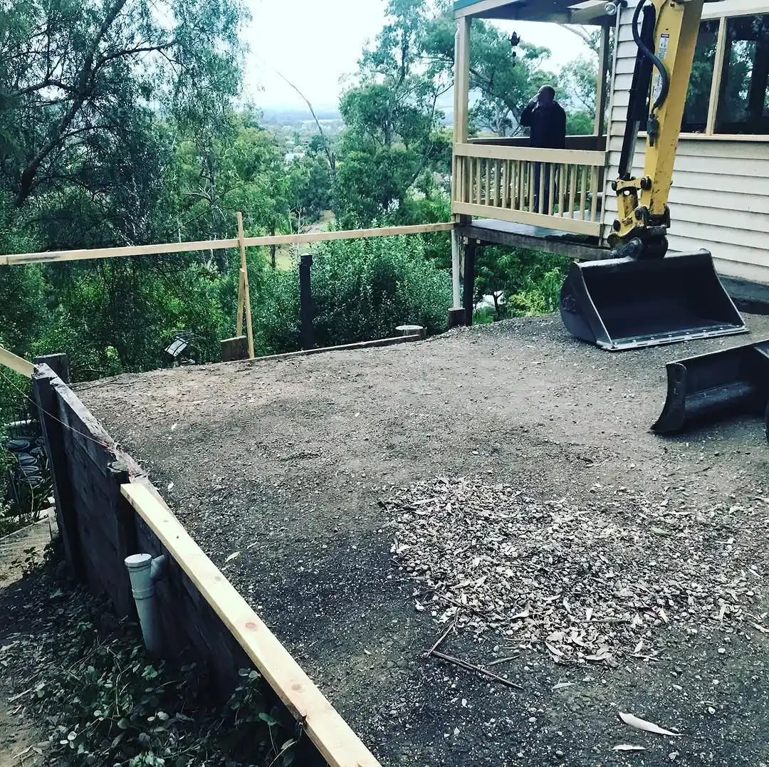 Levelled building platform cut into the hillside block at Healesville, with timber edging and a service pipe at the retained edge