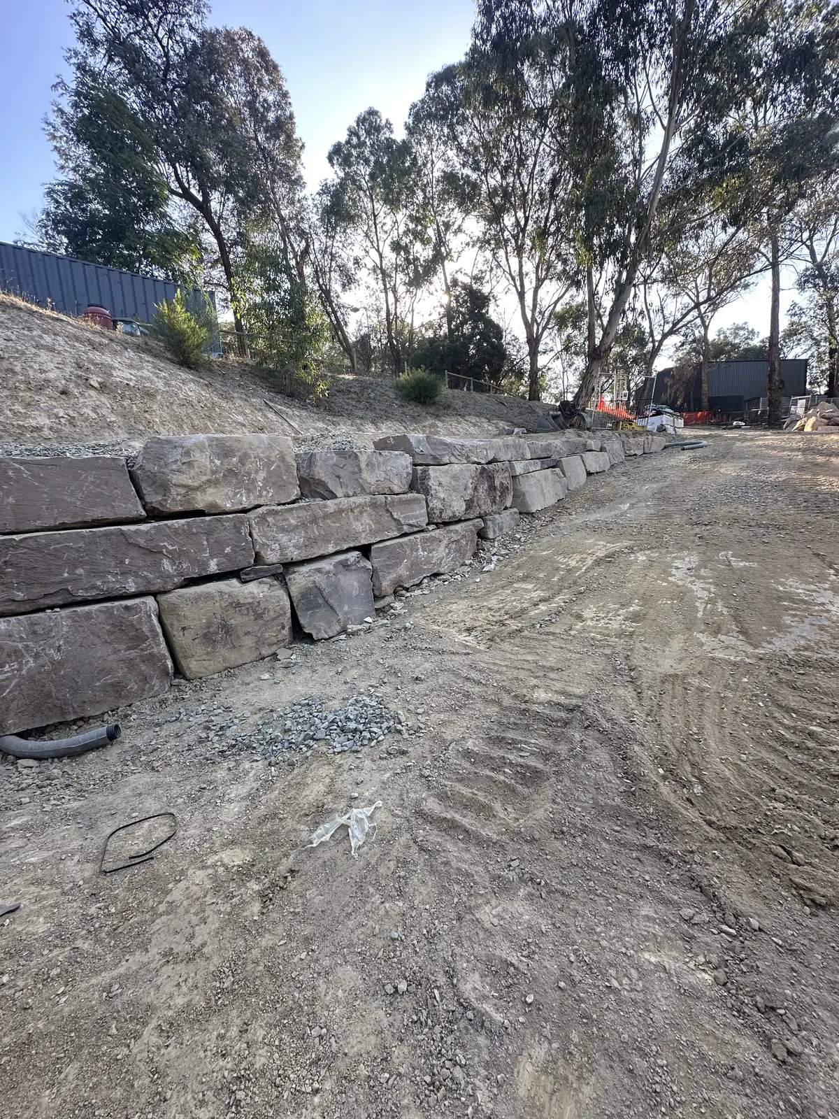 Entire Excavations retaining wall with drainage pipe behind rock