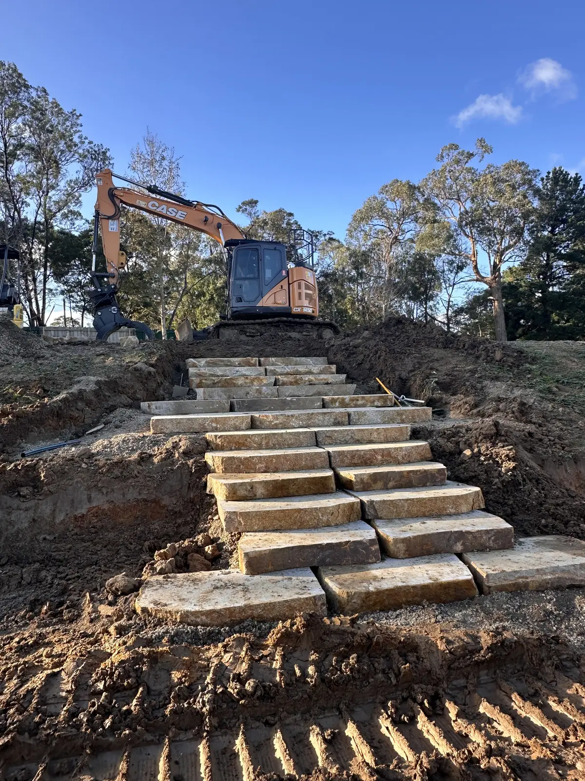 Entire Excavations excavator with rock staged ready for a wall build