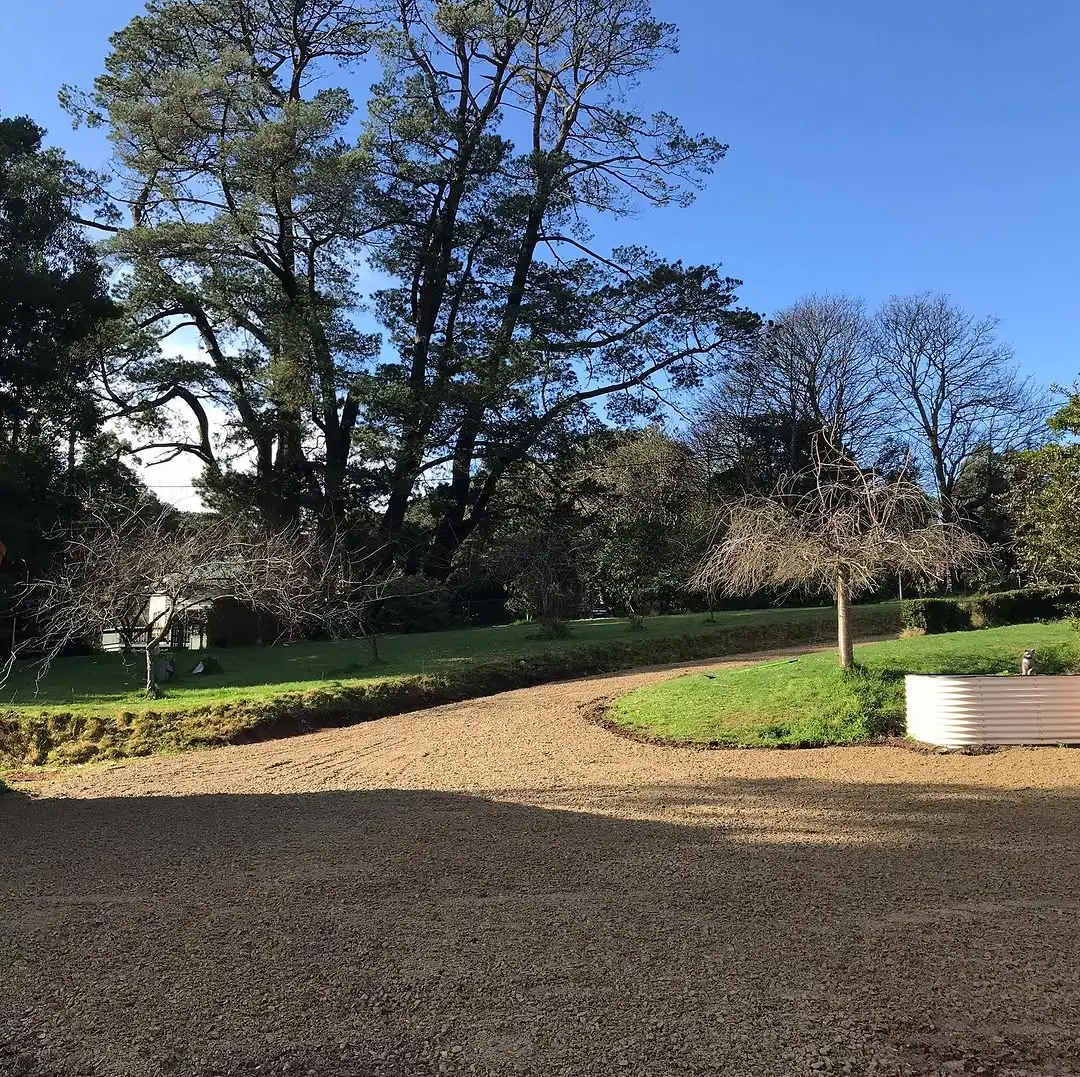 Freshly resurfaced crushed rock driveway curving around a lawn island under tall pine trees in Olinda