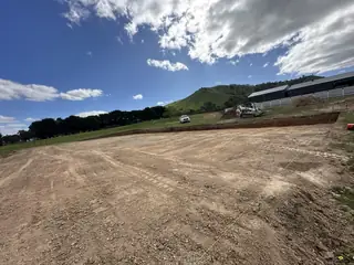 Entire Excavations earthworks site cut with excavator, hills backdrop