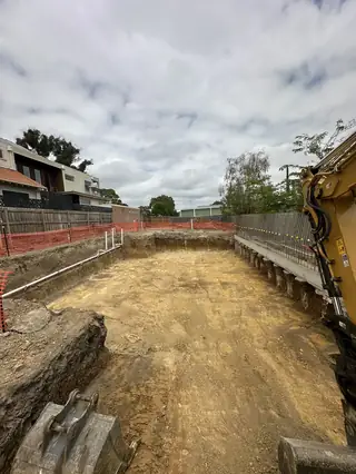 Entire Excavations basement excavation next to a home under construction