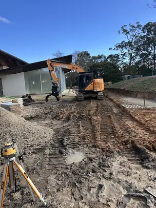 Entire Excavations excavator on a graded site with laser level set up