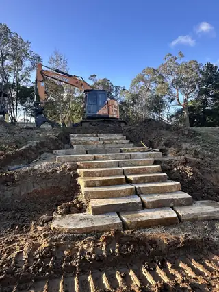 Entire Excavations excavator with rock staged ready for a wall build