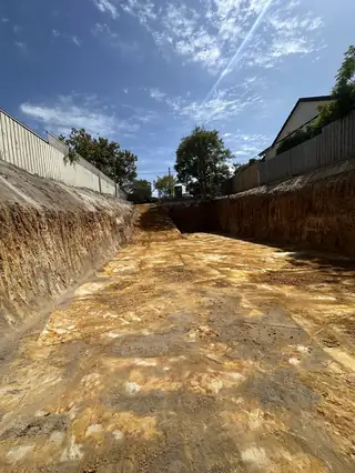 Entire Excavations cut earth bank beside a house during site works